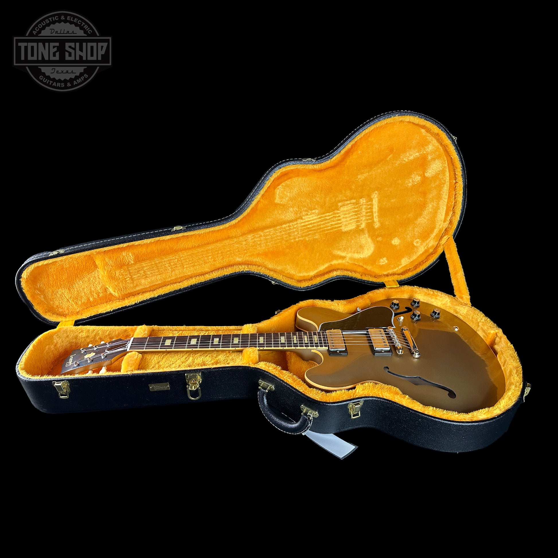 Gibson guitar in an open case with 'Tone Shop' logo.