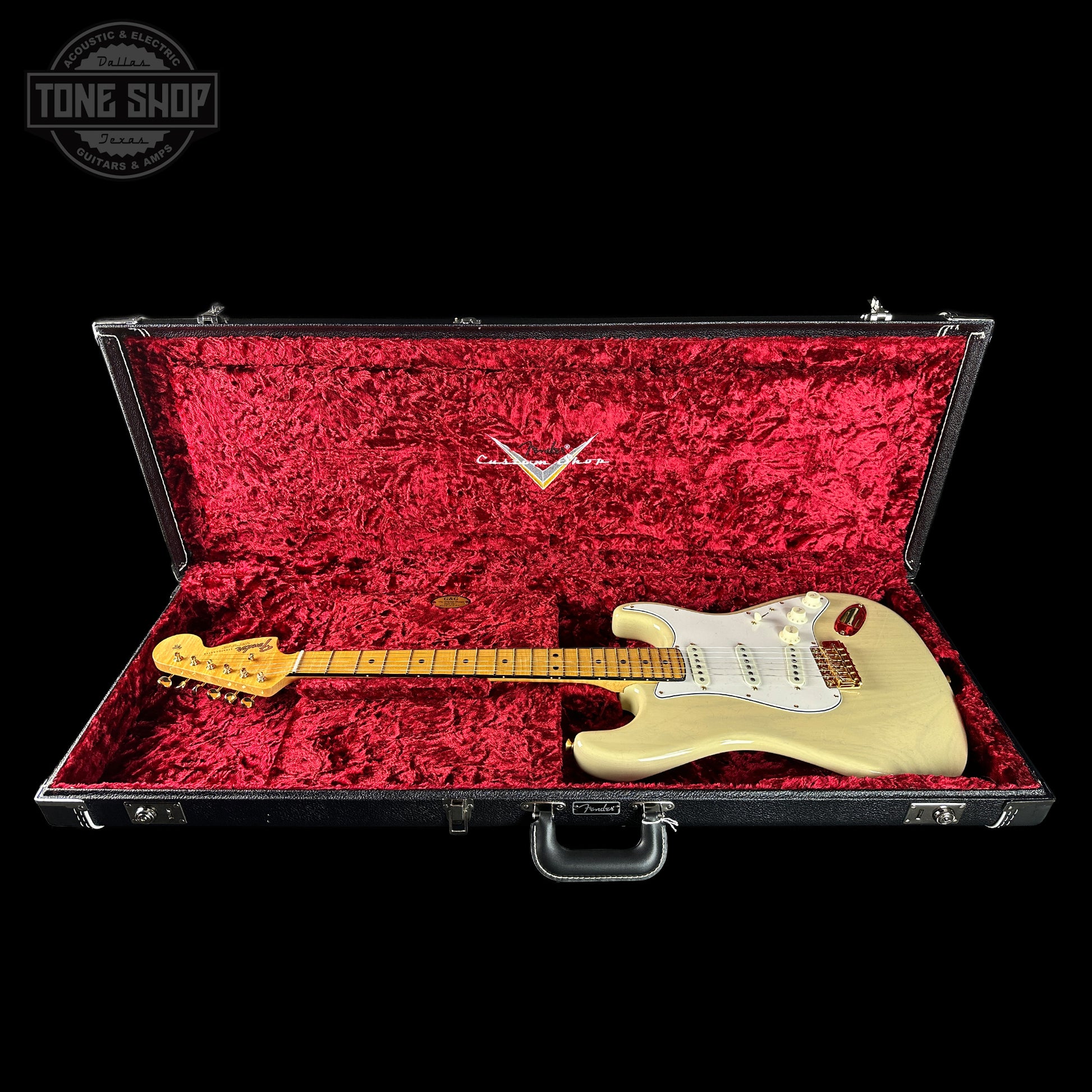 Electric guitar in a red-lined case with a visible brand logo on a black background.