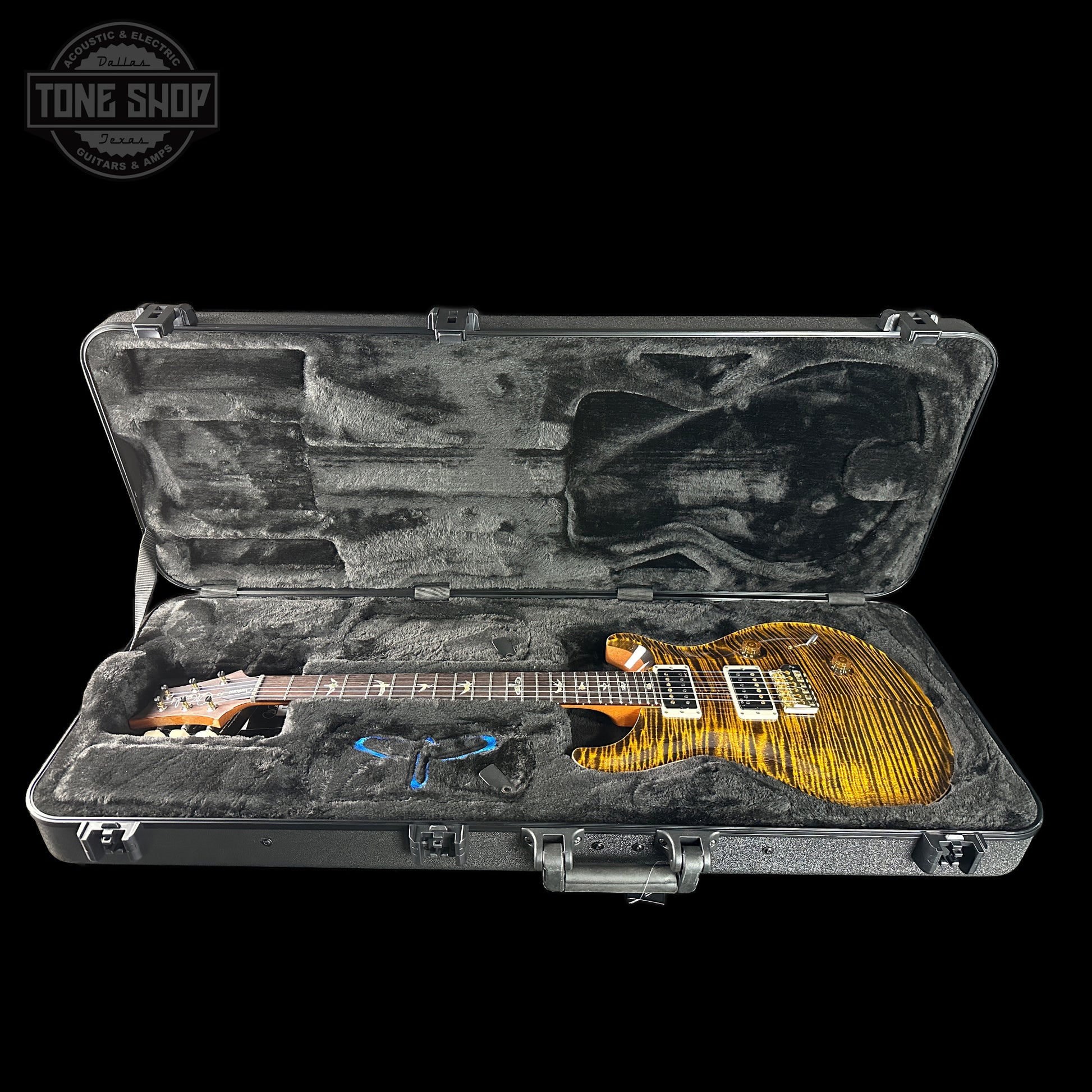 Glossy electric guitar in a hard-shell case with 'Tone Shop' logo.