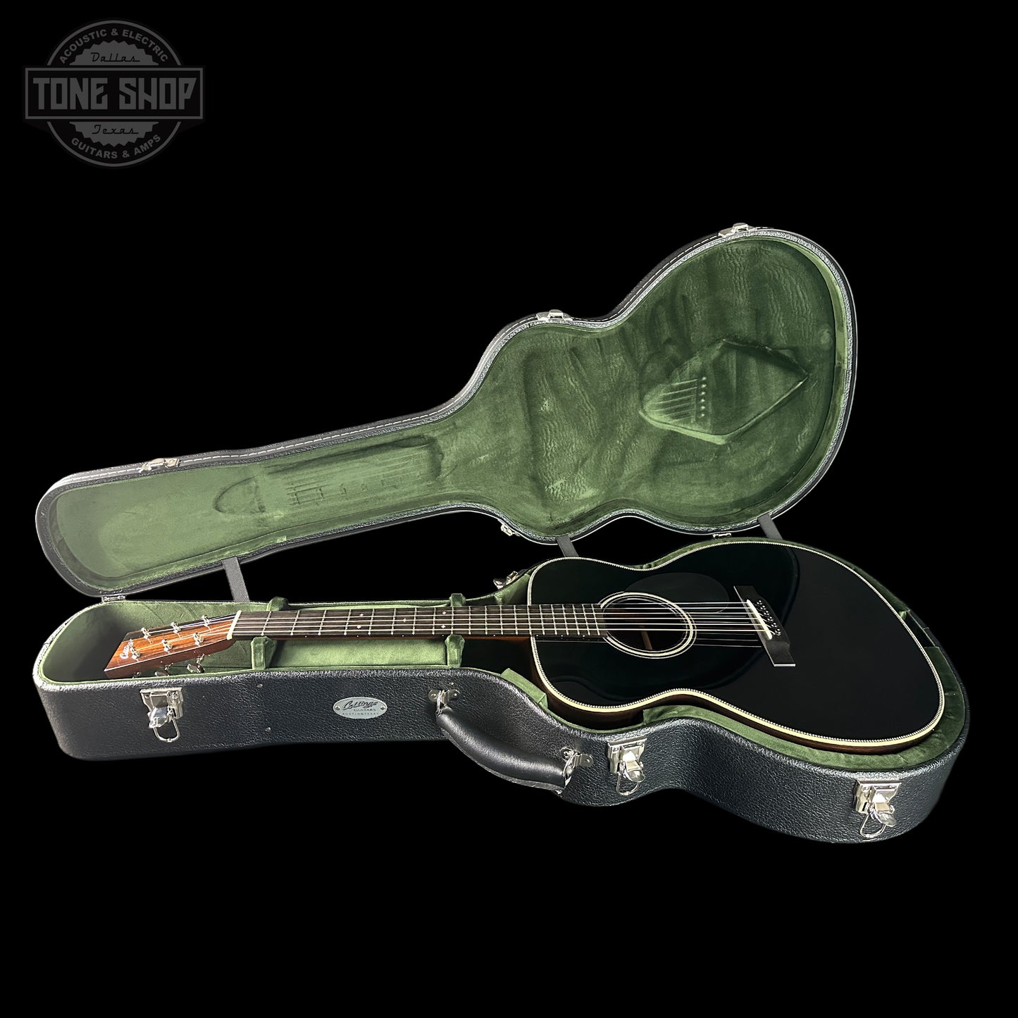 Black acoustic guitar in a green case with 'Tone Shop' logo.