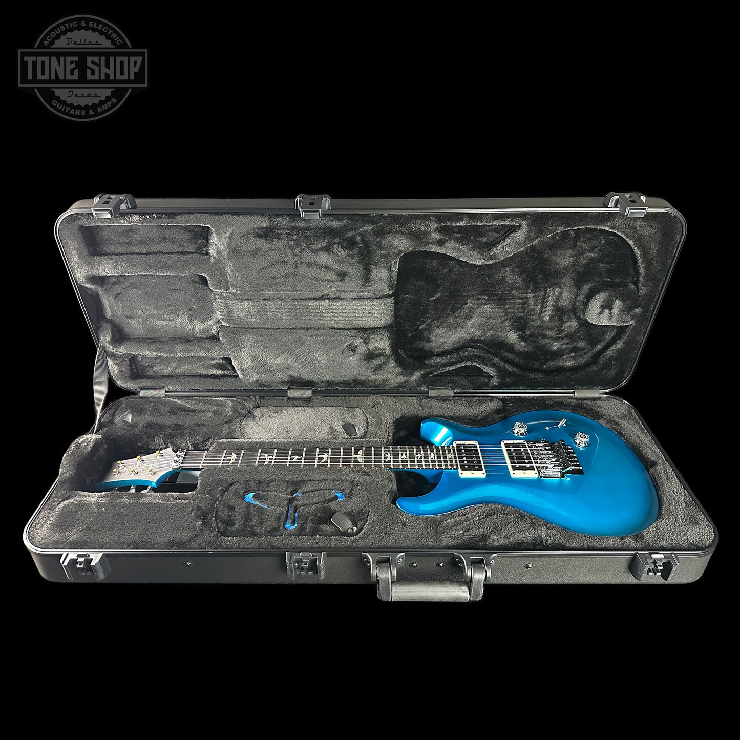 Blue electric guitar in a black case with 'Tone Shop' logo.