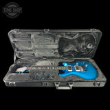 Blue electric guitar in a black case with 'Tone Shop' logo.