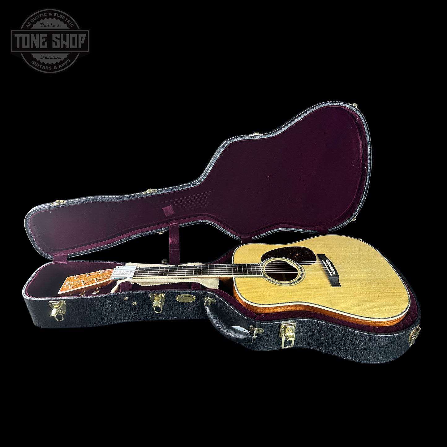 Acoustic guitar in an open case with 'Tone Shop' logo in the corner.