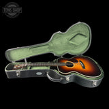 Acoustic guitar in a hard-shell case with 'Tone Shop' logo.