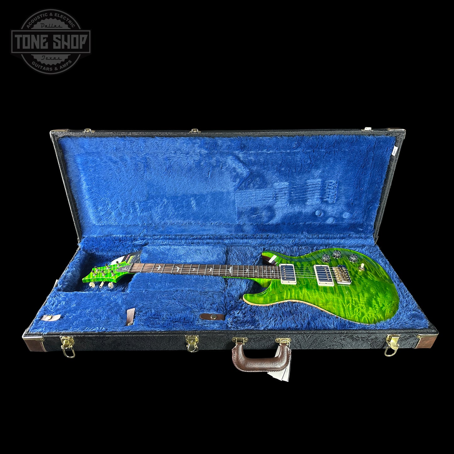 Green electric guitar in a blue case with 'Tone Shop' logo.
