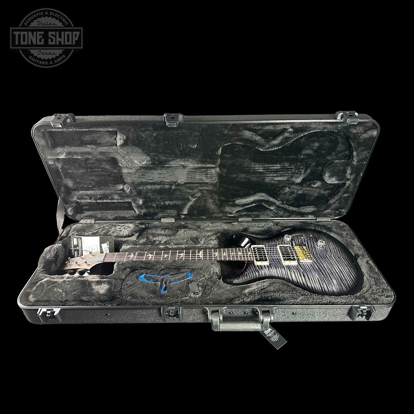 Guitar in a hard-shell case with 'Tone Shop' logo in the corner.