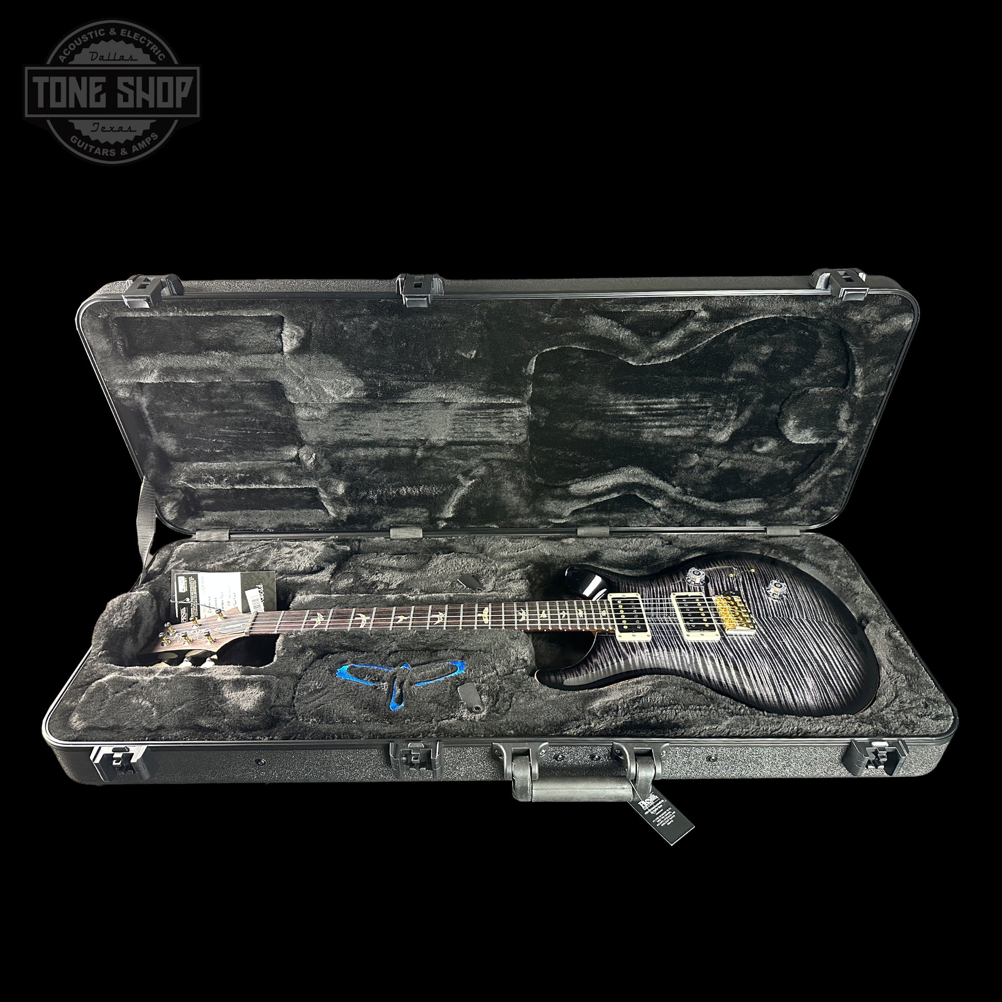 Guitar in a hard-shell case with 'Tone Shop' logo in the corner.