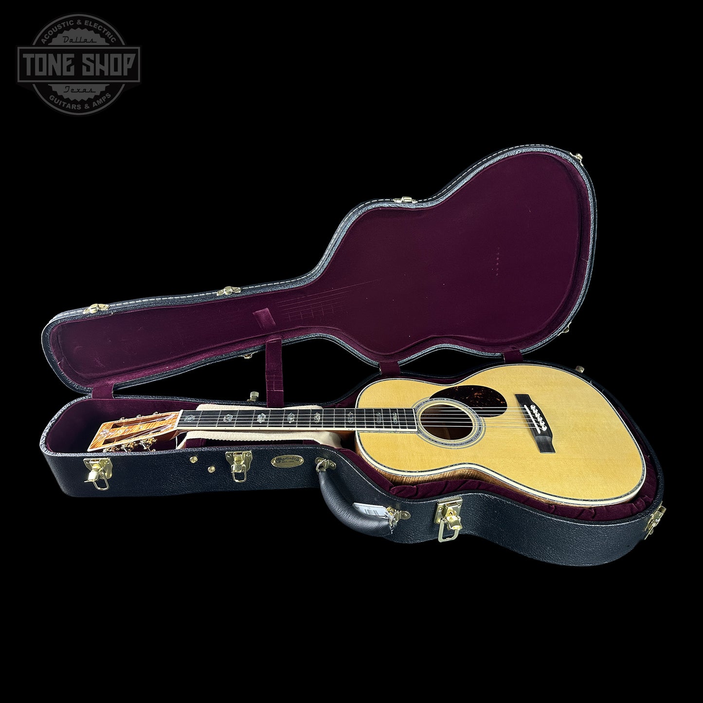 Acoustic guitar in a hard-shell case with 'Tone Shop' logo.
