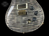 Close-up of a guitar's body with a zebra wood finish on a black background