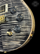 Close-up of a guitar's control knobs and tuning pegs with 'Tone Shop' logo.