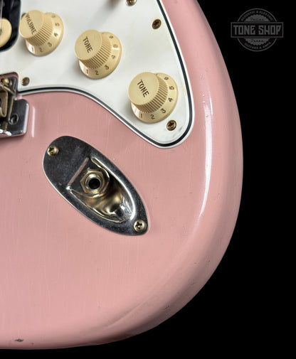 Close-up of a pink electric guitar with gold control knobs on a black background, featuring 'Tone Shop' branding.