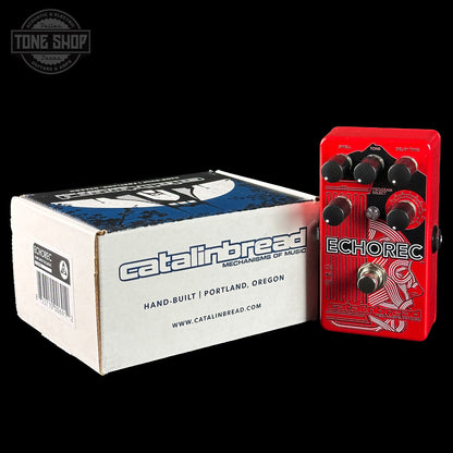 Red Catalinbread Echorec guitar effects pedal next to its packaging box on a black background.
