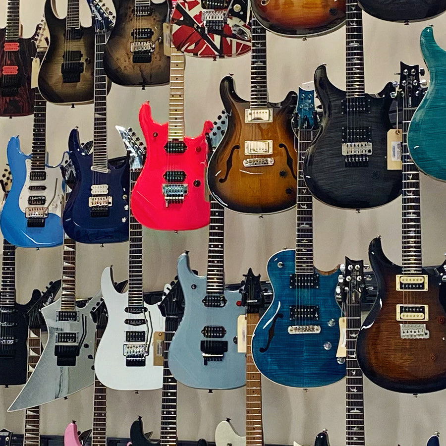 Colorful electric guitars hanging in display showroom at Tone Shop Guitars.