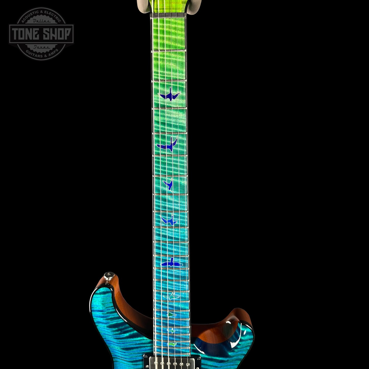 Close-up of a blue and green electric guitar with a black background