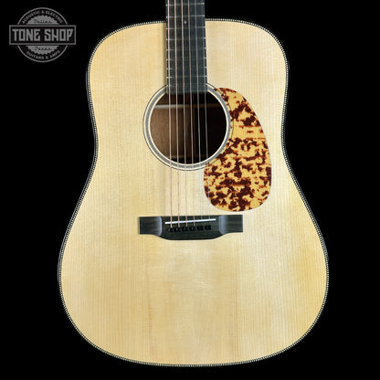 Acoustic guitar with a tortoiseshell pickguard on a black background, featuring the Tone Shop logo.
