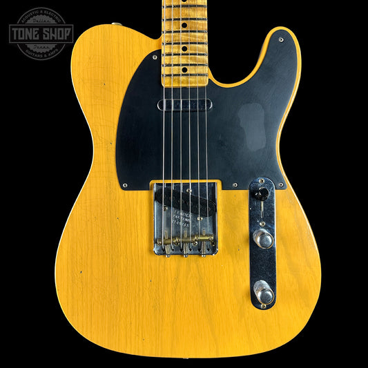 Yellow electric guitar with a black pickguard on a black background, featuring 'Tone Shop' logo.