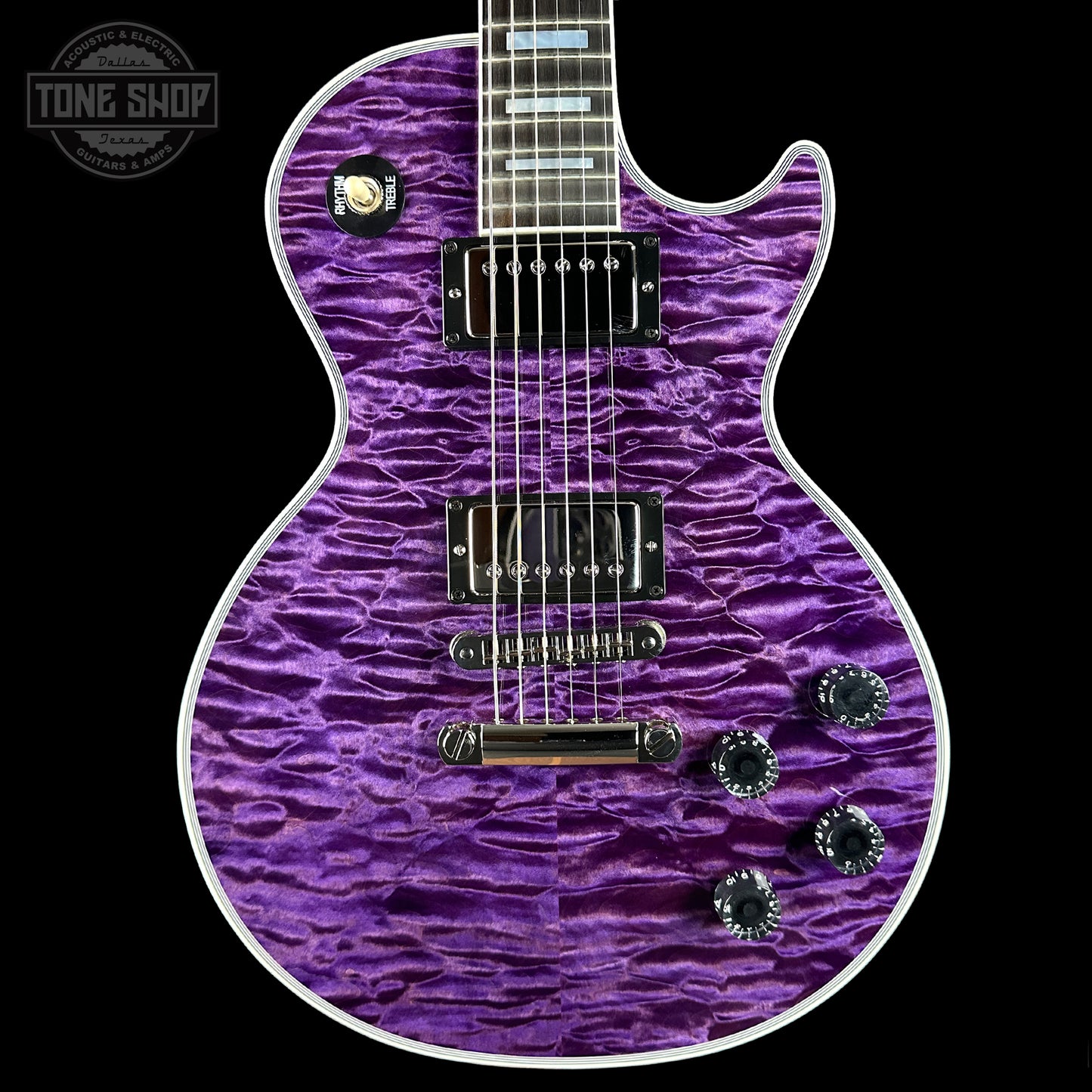 Purple electric guitar with a wavy pattern on a black background, featuring the Tone Shop logo.