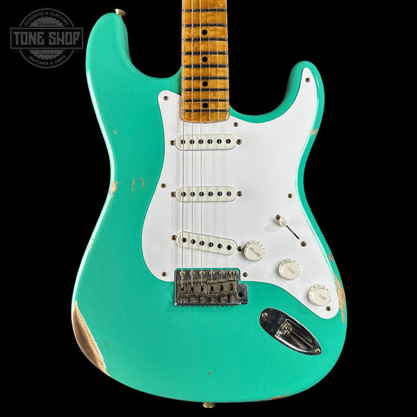 Turquoise electric guitar with a white pickguard on a black background, featuring the Tone Shop logo.