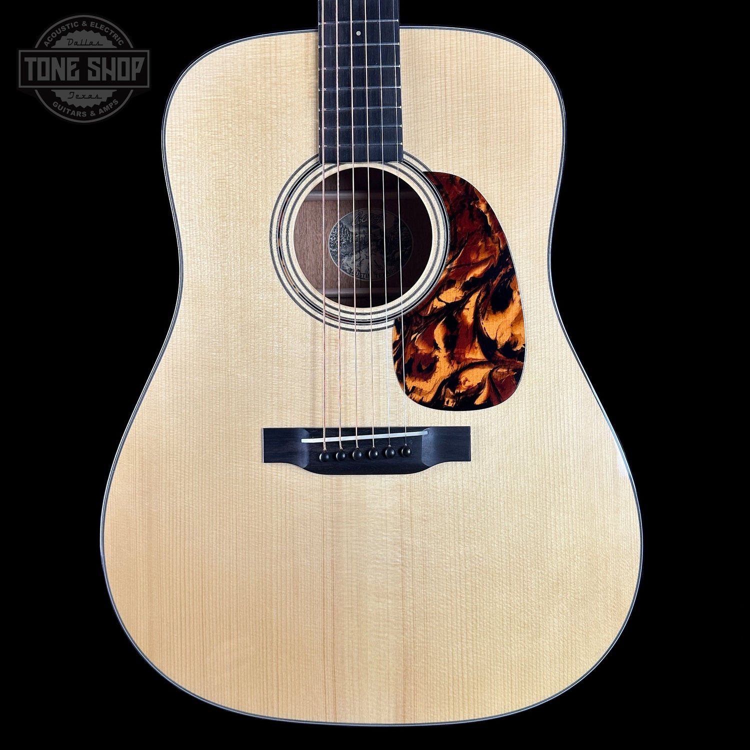 Acoustic guitar with tortoiseshell pickguard on a black background, featuring 'Tone Shop' logo.