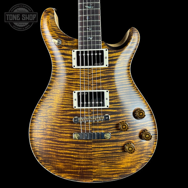 Wooden electric guitar with a wavy grain pattern on a black background, featuring the Tone Shop logo.