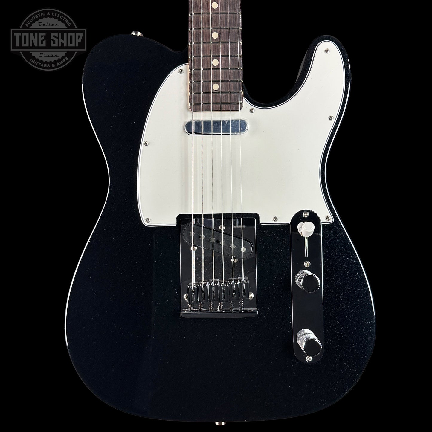 Black electric guitar with a white pickguard on a black background, featuring the Tone Shop logo.