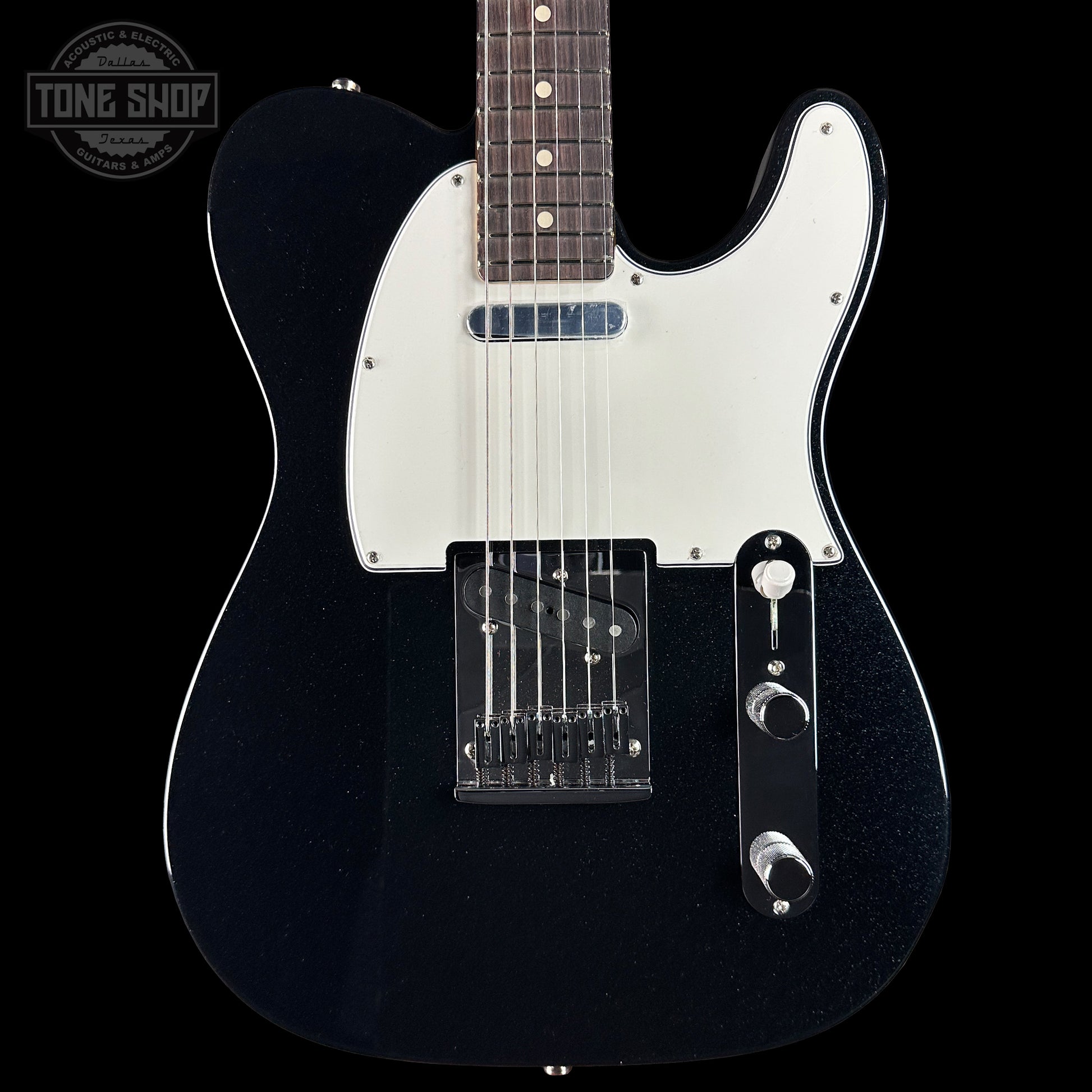 Black electric guitar with a white pickguard on a black background, featuring the Tone Shop logo.