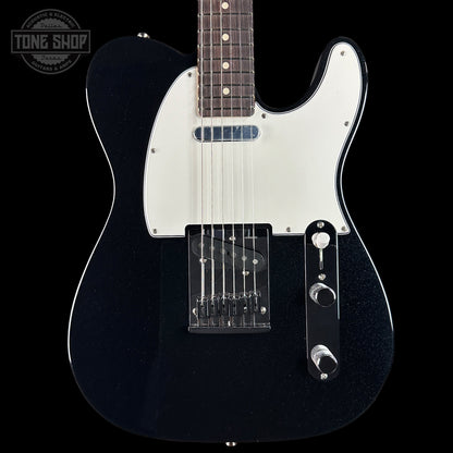 Black electric guitar with a white pickguard on a black background, featuring the Tone Shop logo.