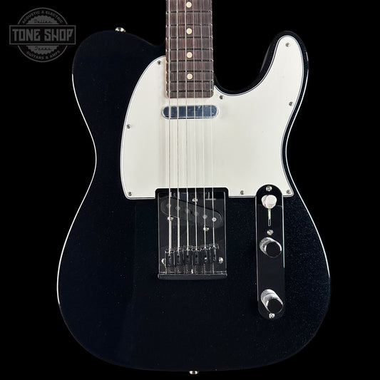 Black electric guitar with a white pickguard on a black background, featuring the Tone Shop logo.