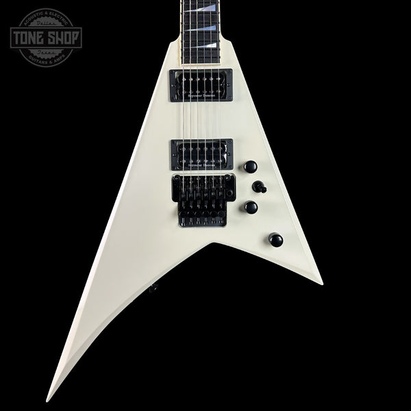 White electric guitar with a black pickguard on a black background, featuring the Tone Shop logo.