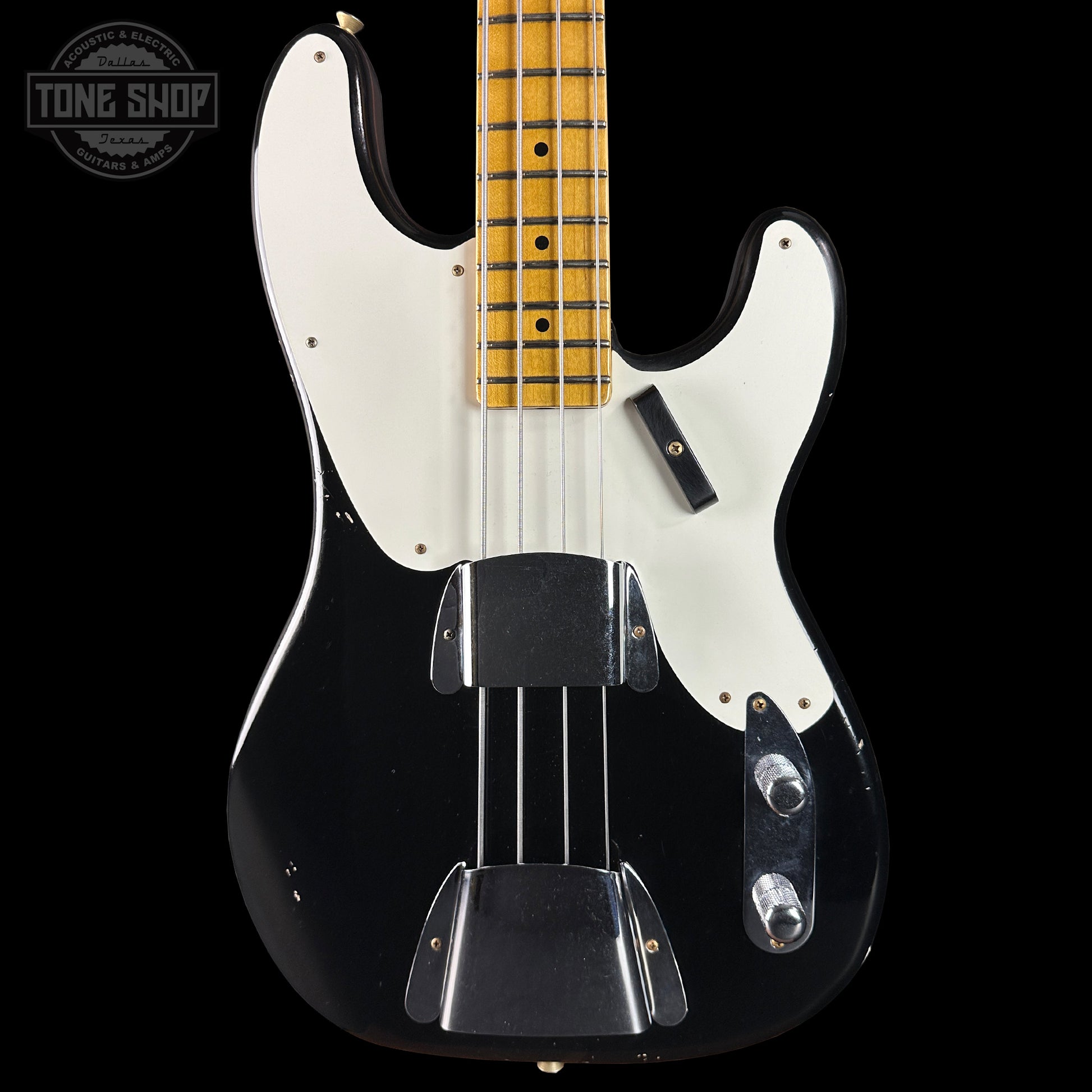 Black electric bass guitar with a white pickguard on a black background, featuring 'Tone Shop' branding.