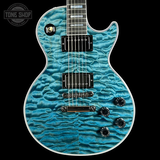 Blue electric guitar with a wavy finish on a black background, featuring the Tone Shop logo.