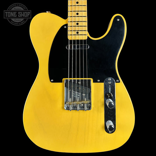 Yellow electric guitar with a black pickguard on a black background, featuring the Tone Shop logo.