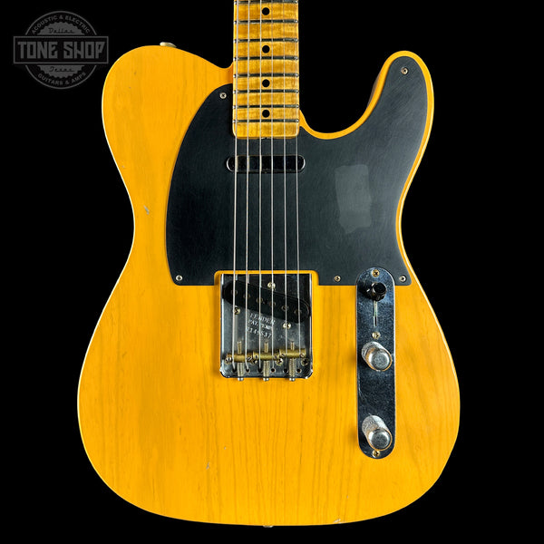 Yellow electric guitar with a black pickguard on a black background, featuring 'Tone Shop' logo.