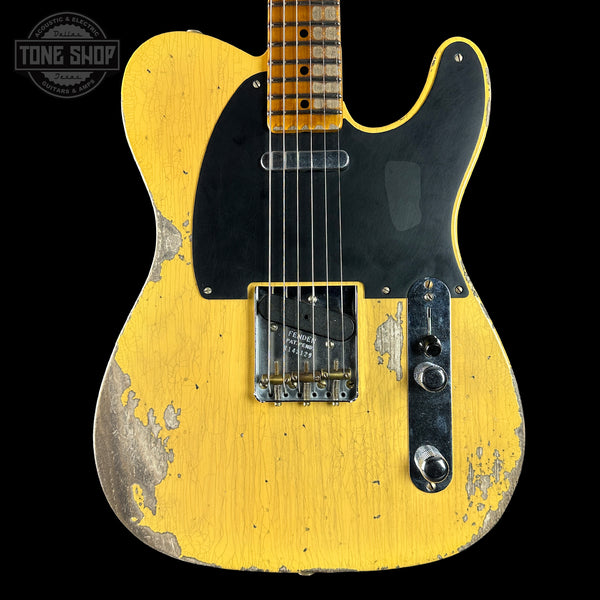 Yellow electric guitar with a worn finish on a black background, featuring the 'Tone Shop' logo.