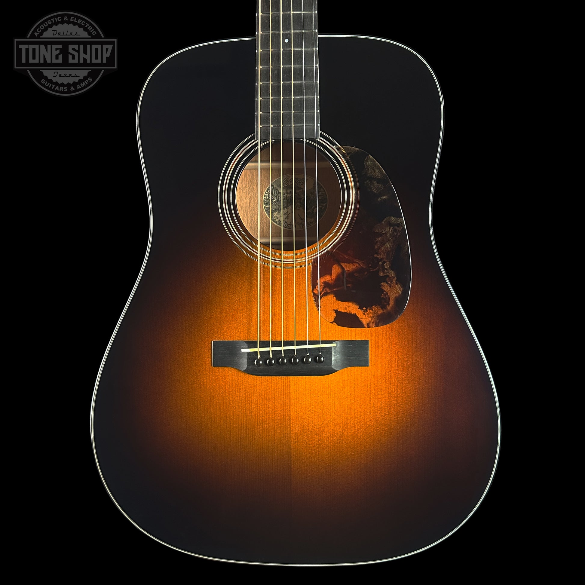 Acoustic guitar with a sunburst finish on a black background, featuring the Tone Shop logo.