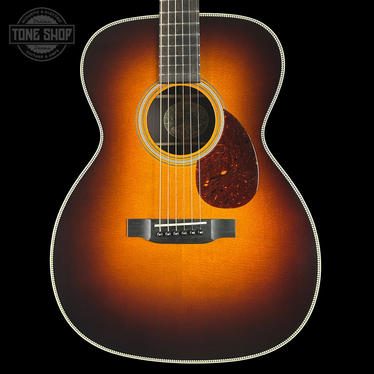 Acoustic guitar with a sunburst finish on a black background, featuring the Tone Shop logo.