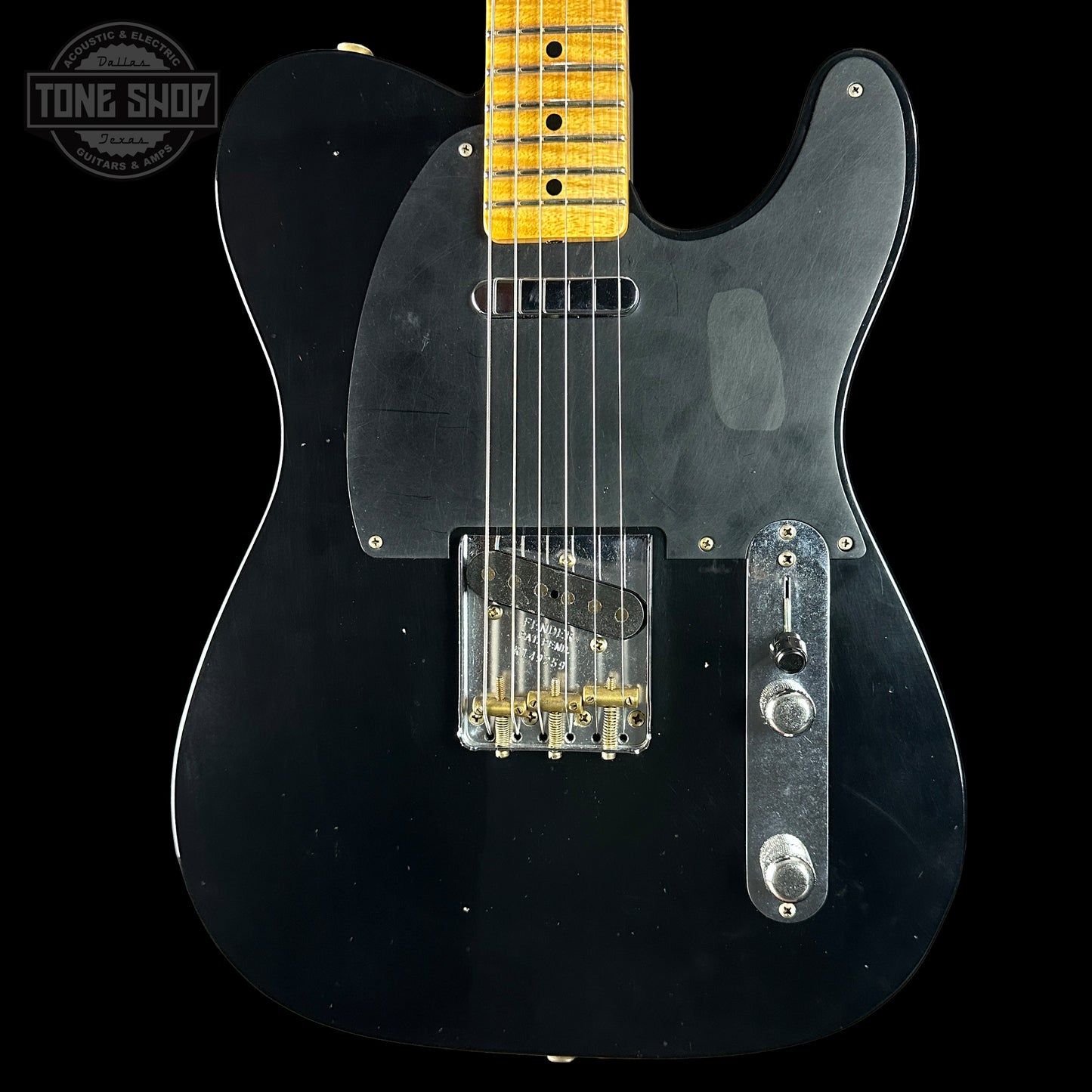 Black electric guitar with a yellow fretboard on a black background, featuring the Tone Shop logo.