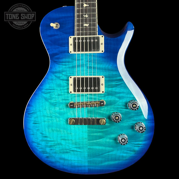 Blue electric guitar with a black pickguard on a black background, featuring the Tone Shop logo.