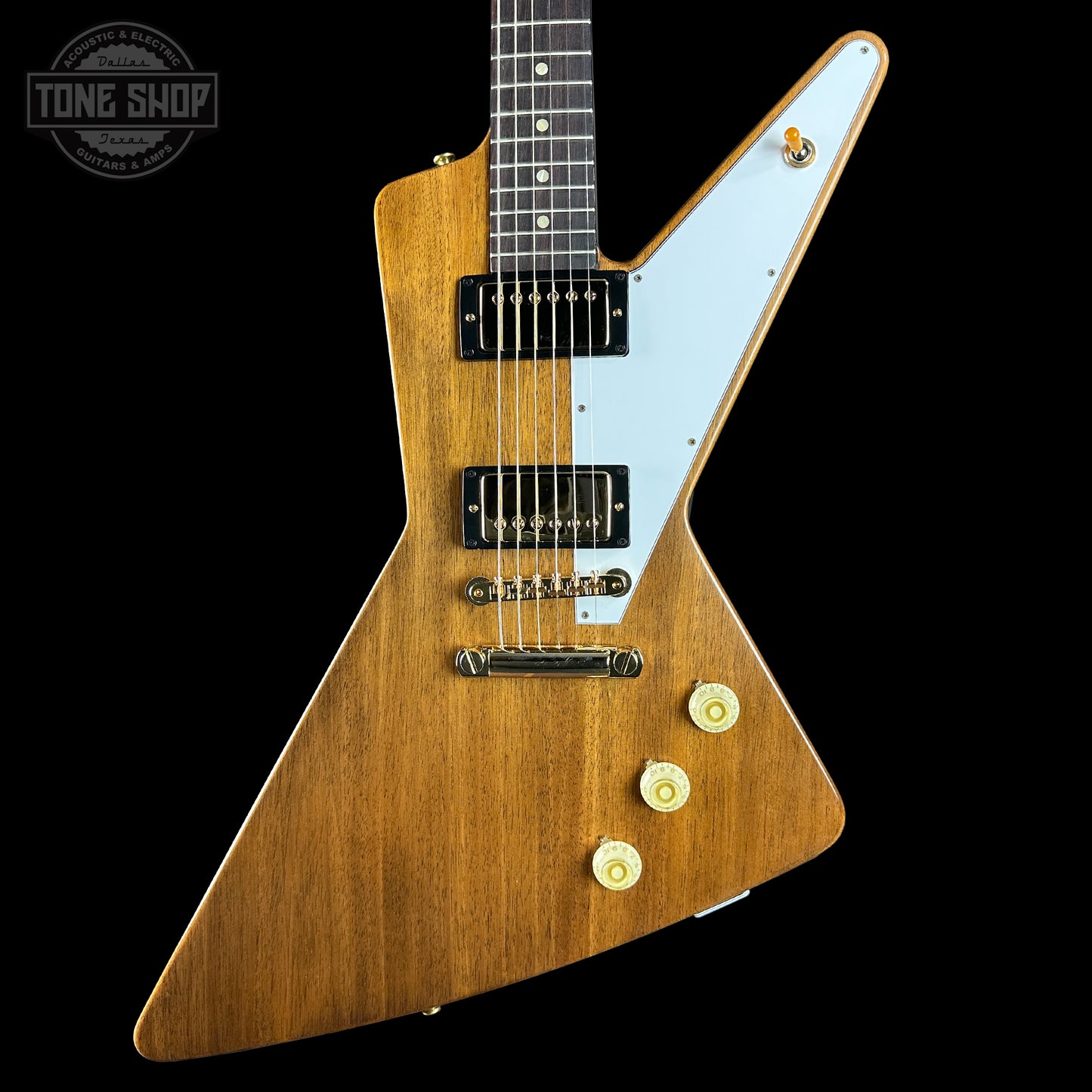 Wooden electric guitar with a white pickguard on a black background, featuring the Tone Shop logo.