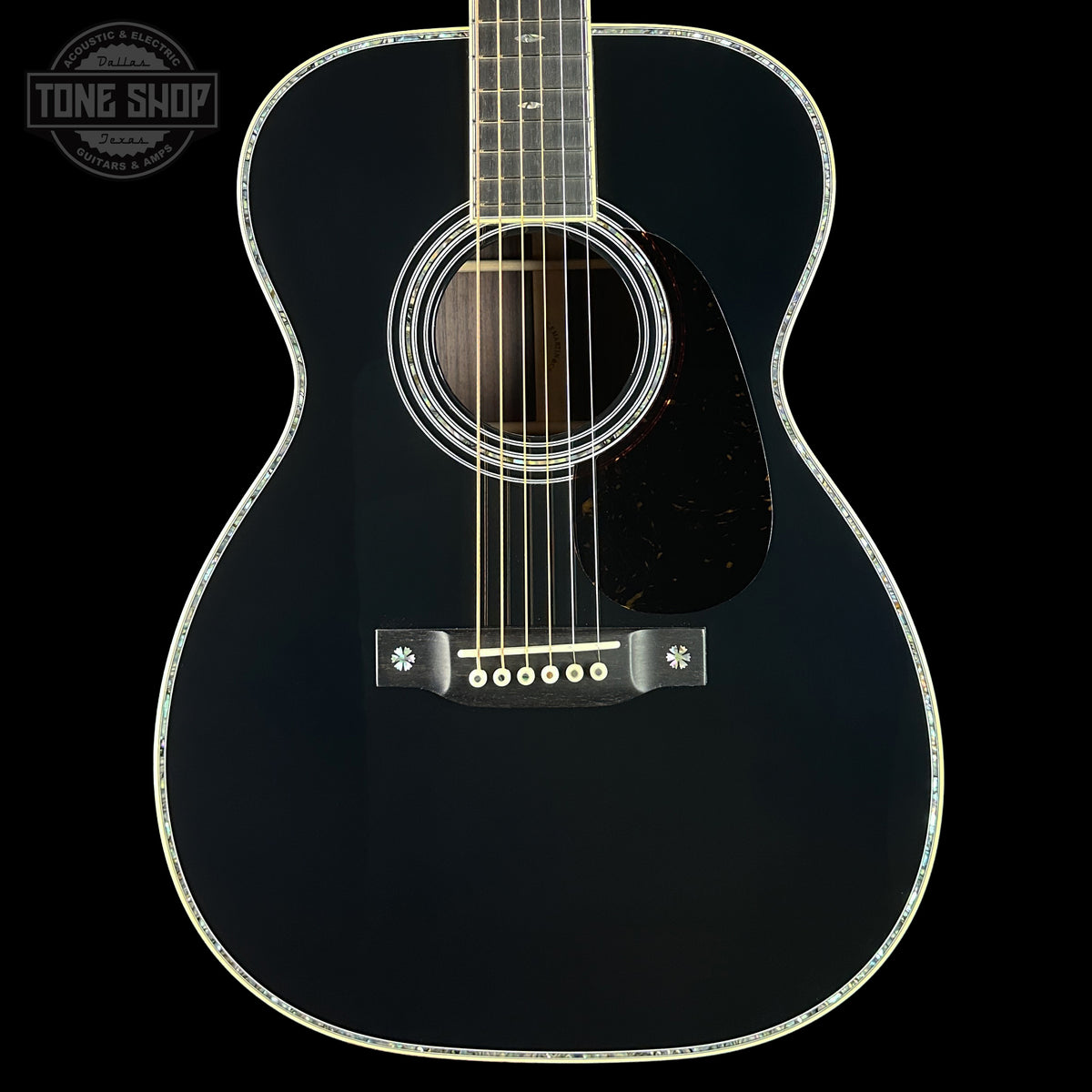 Black acoustic guitar on a black background with 'Tone Shop' logo.