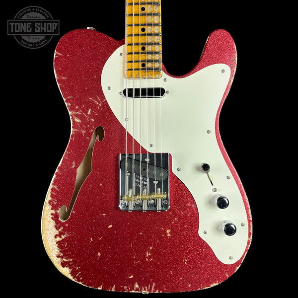 Red electric guitar with white pickguard on a black background, featuring 'Tone Shop' logo.