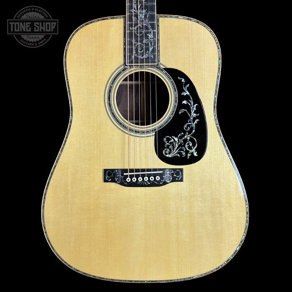 Acoustic guitar with decorative inlay on a black background, featuring the Tone Shop logo.
