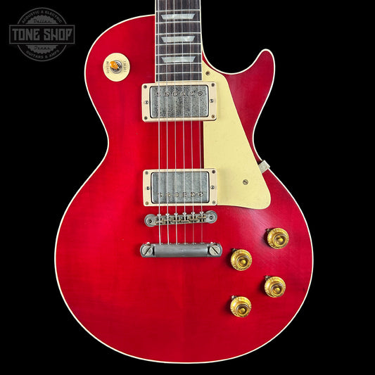 Red electric guitar with gold hardware on a black background, featuring 'Tone Shop' logo.