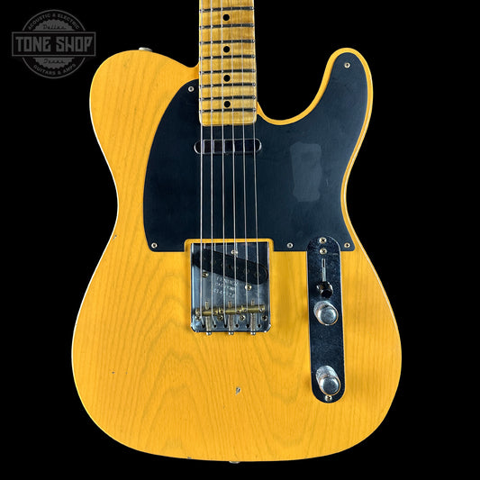 Yellow electric guitar with a black pickguard on a black background, featuring 'Tone Shop' branding.