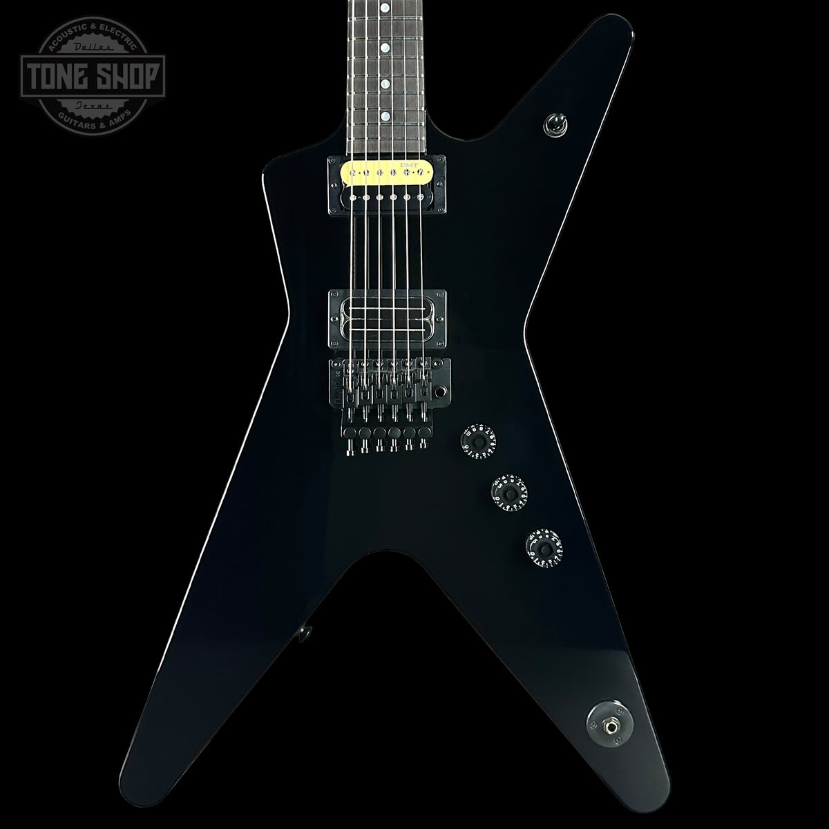 Black electric guitar with a unique body shape on a black background, featuring the 'Tone Shop' logo.