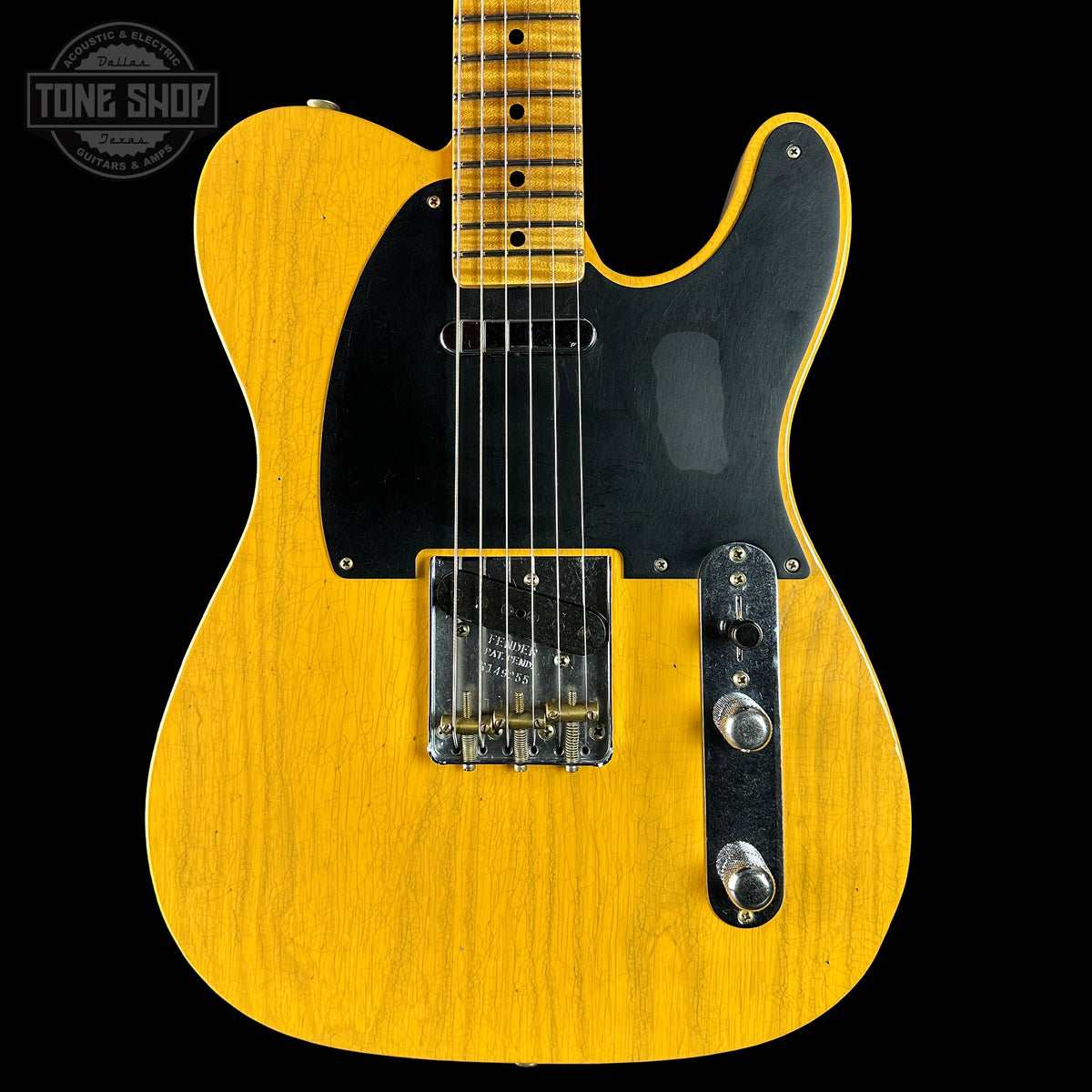 Yellow electric guitar with a black pickguard on a black background, featuring 'Tone Shop' branding.