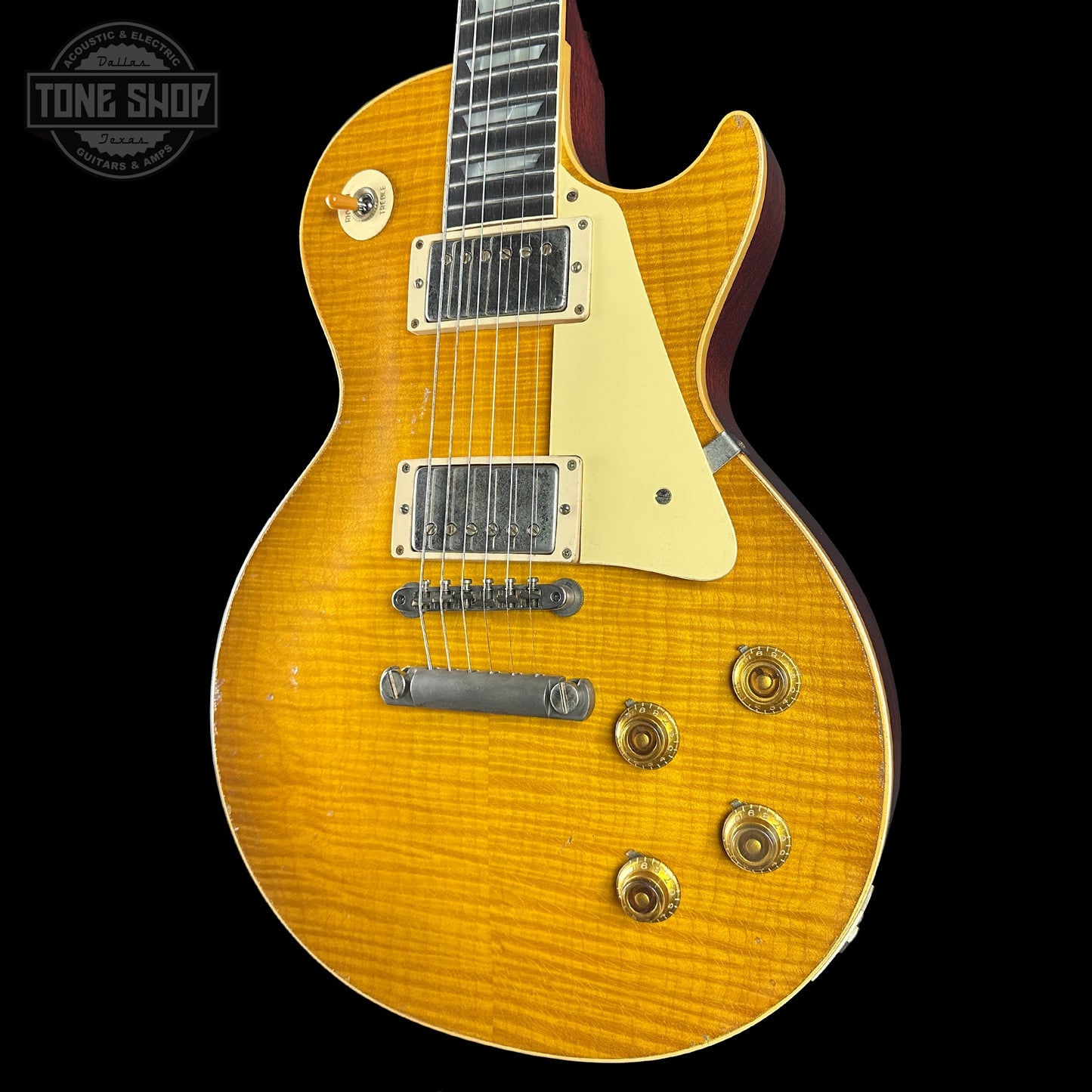 Yellow electric guitar with a black background, featuring the Tone Shop logo.