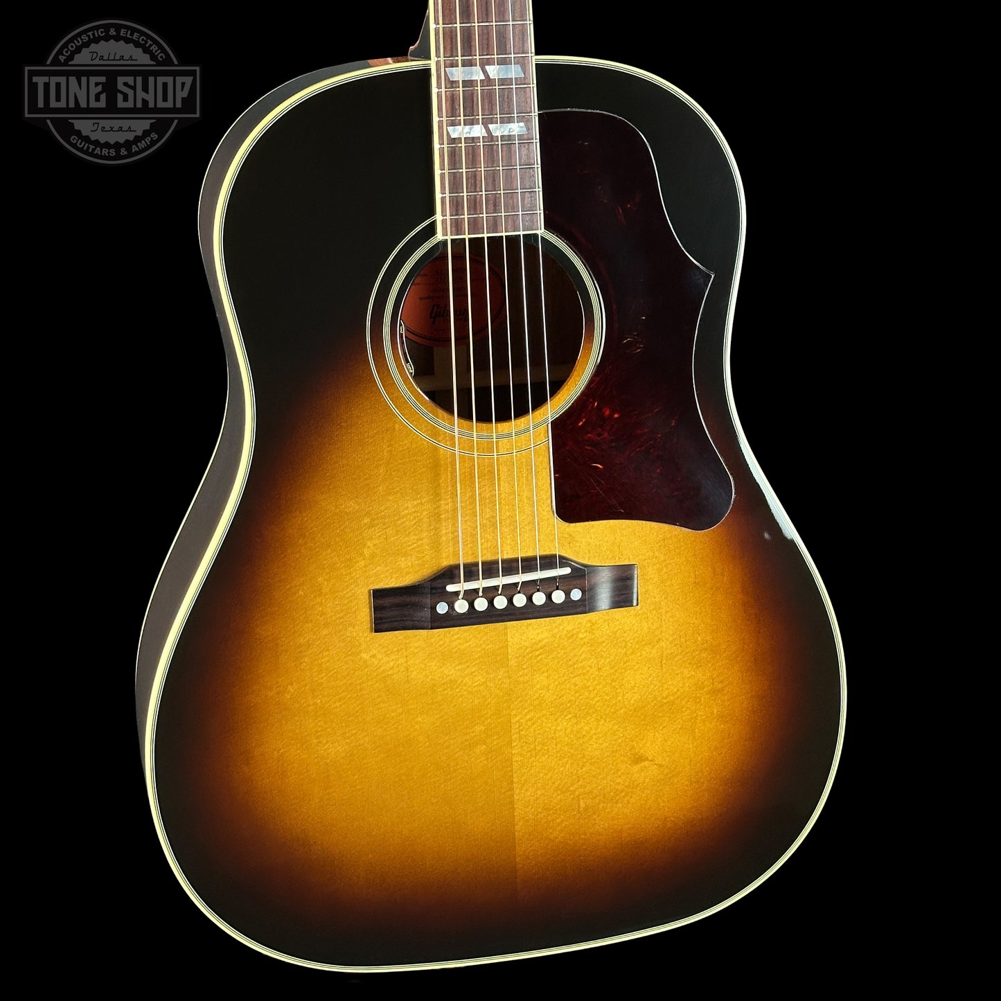 Acoustic guitar with a sunburst finish on a black background, featuring the Tone Shop logo.