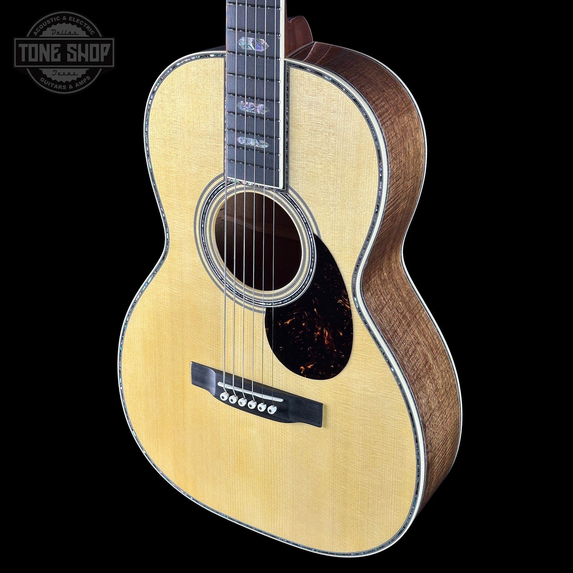 Acoustic guitar with a visible brand logo on a black background