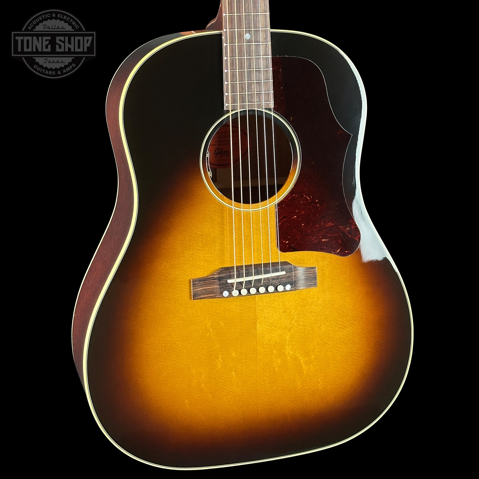 Acoustic guitar with a sunburst finish on a black background, featuring the Tone Shop logo.